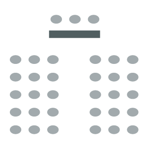Two sections of seating with central aisle between; rectangular table with chairs for presenters at front of room